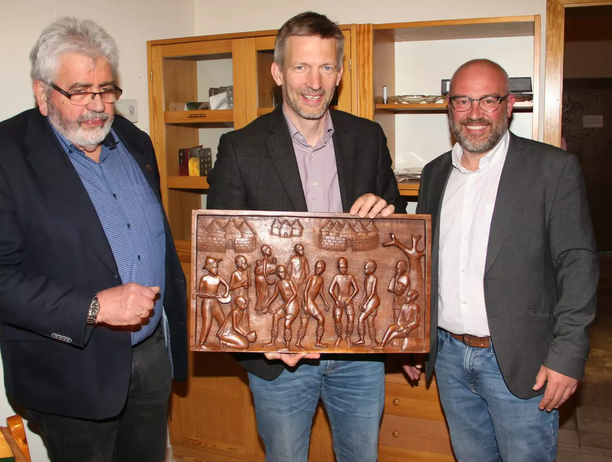 Bürgermeister Schmutz hält das Holzrelief, das ihm Gerhard Kleinböck (links) und Markus Bündig (rechts) überreicht haben